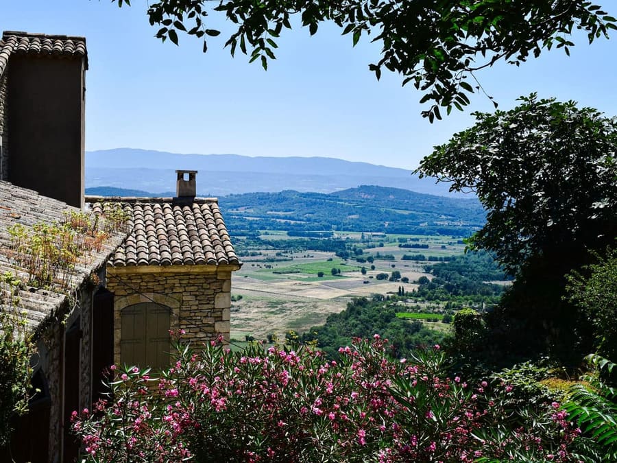 Toits de tuiles d'un village provençal dominant la vallée et les collines boisées